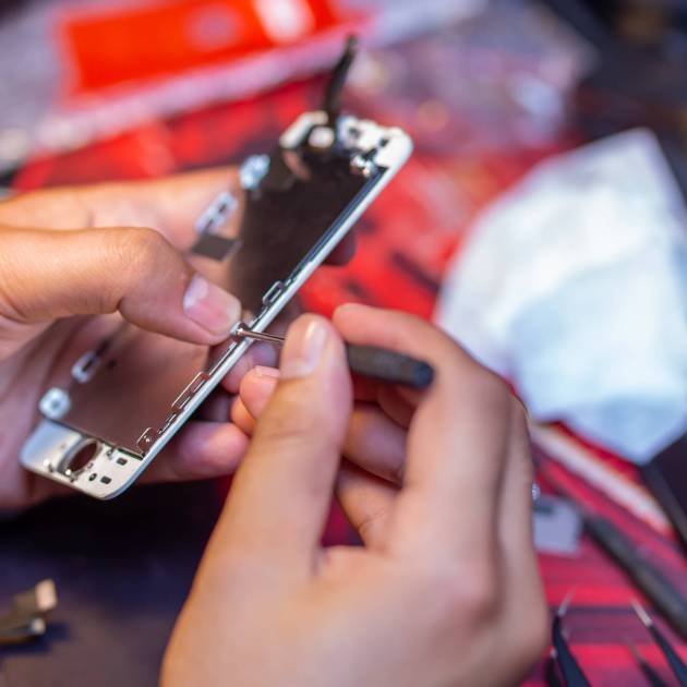 A man is repairing a mobile phone. In the frame, his hands and details of the device. repair shop for gadgets.